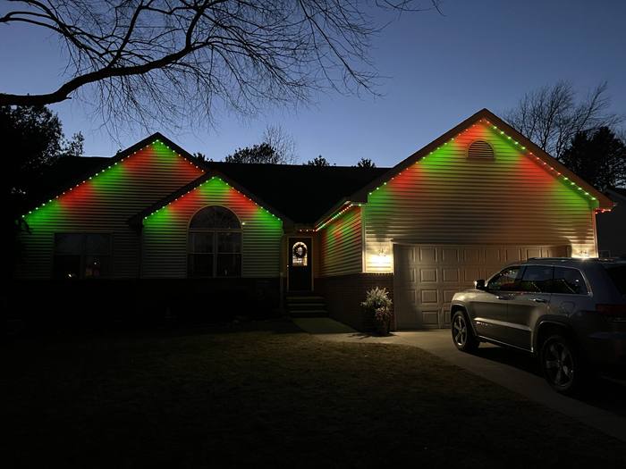 Ranch home with red and green Trimlight roofline lighting at dusk