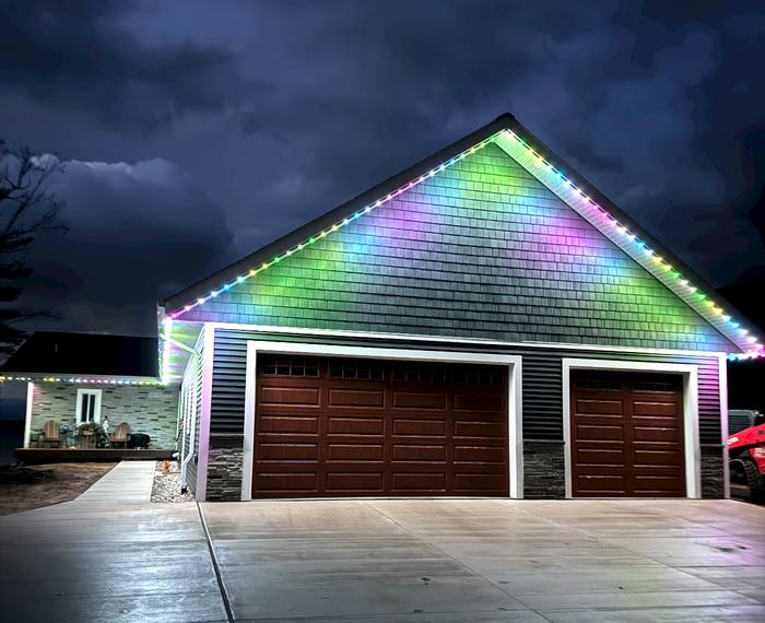 Garage gable with rainbow Trimlight gradient under a stormy sky