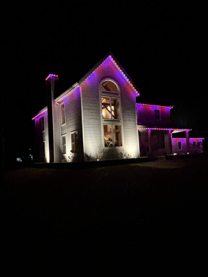 Two-story home with purple and pink Trimlight at dusk