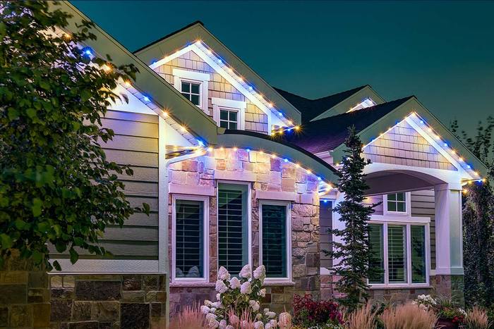 Craftsman home with warm white and blue Trimlight accent at twilight