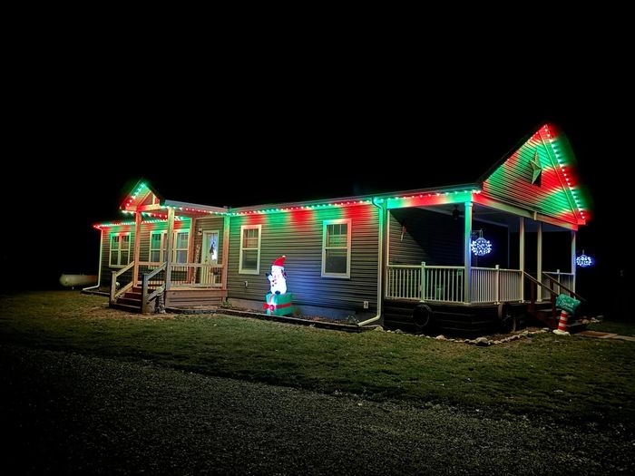 Ranch home with red and green Trimlight roofline lighting and inflatable snowman in the yard