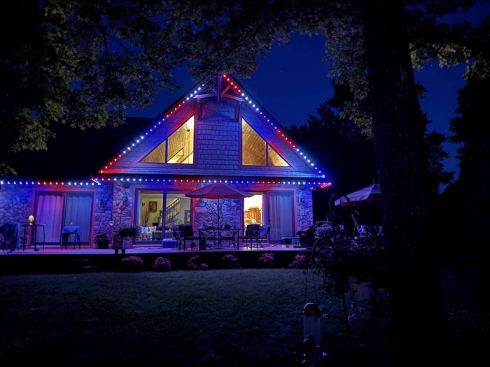 A-frame home deck and roofline lit with blue and red Trimlight