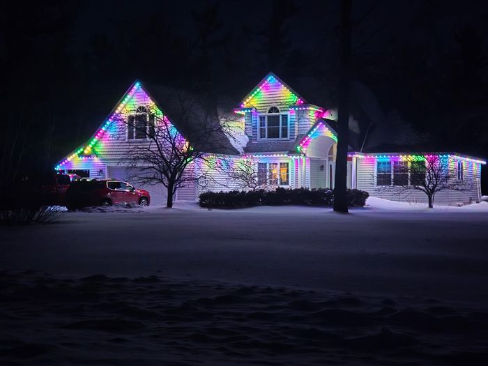 Two-story home with colorful rainbow Trimlight along multiple gables