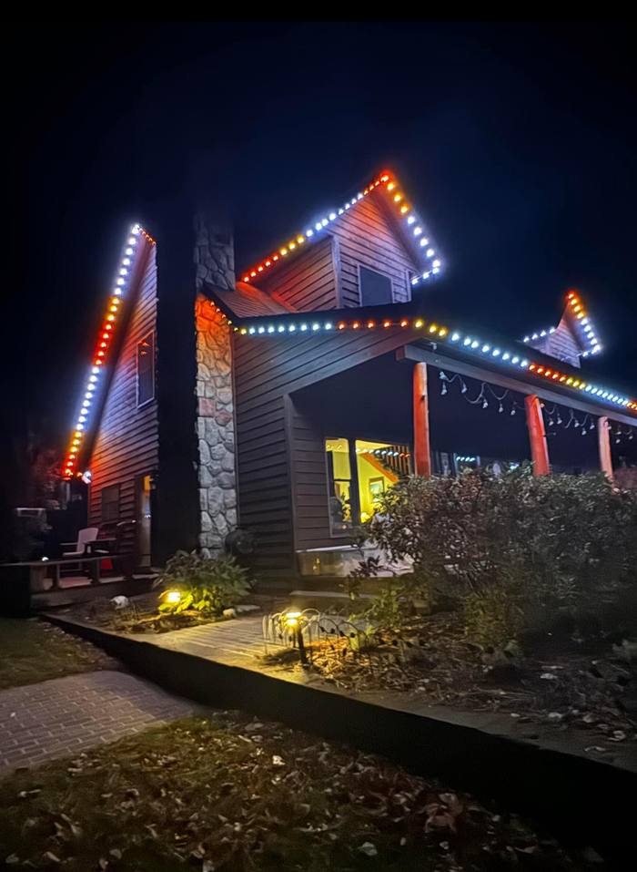 Rustic cabin with red, white, and blue Trimlight installation