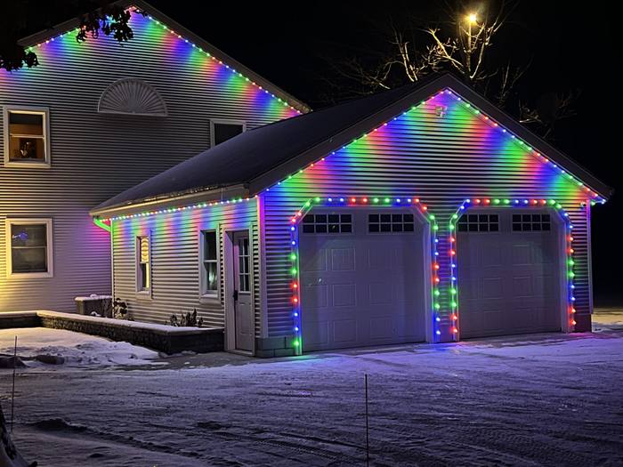 Home with multicolor rainbow Trimlight along two gables and garage