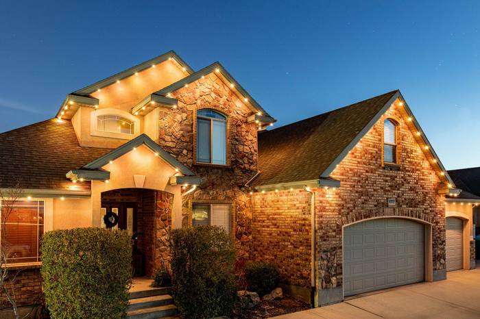 Elegant two-story stone and brick home with warm white Trimlight accent