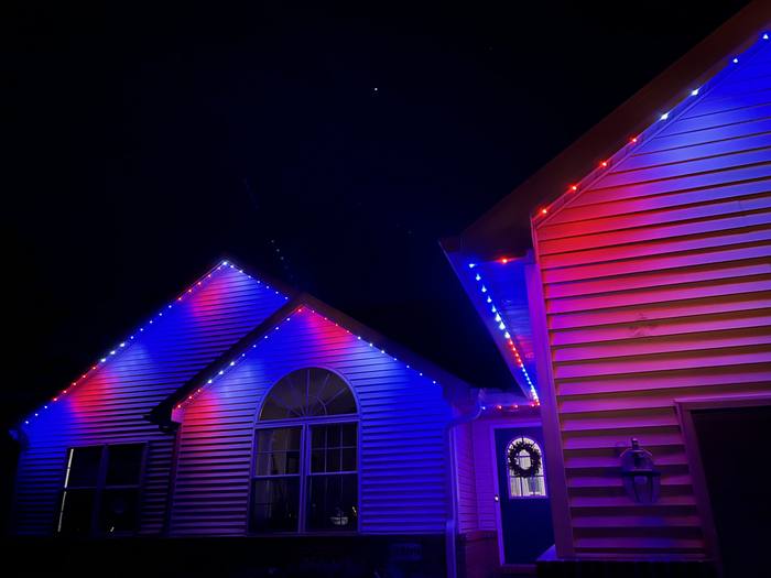 Home with blue and red Trimlight along two rooflines at night